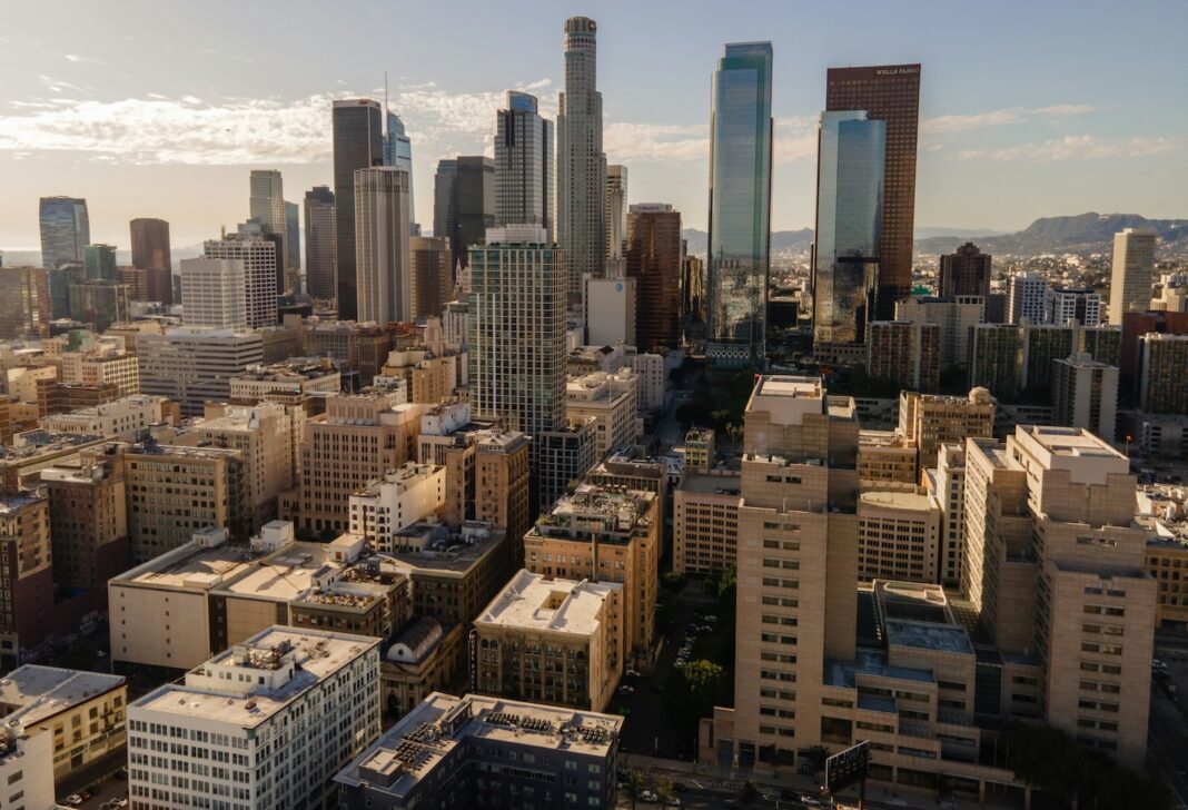 Aerial view of the Los Angeles skyline with skyscrapers under a clear blue sky.
